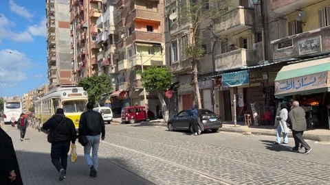 Yellow tram passing through a busy street in Alexandria, Egypt Stock Footage 317870699