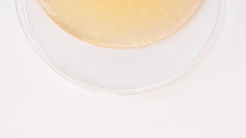 Yellow Transparent Cosmetic Gel Cream With Molecule Bubbles Flowing On The Plain Stock Footage 166360388
