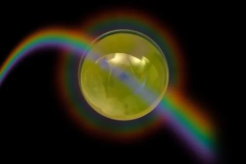 Yellow transparent sphere with rainbow reflections on a black background Stock Photos