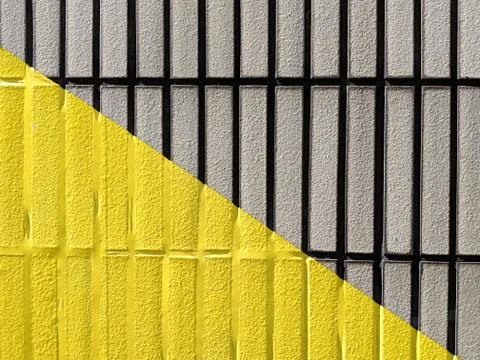 Yellow triangle on a tiled wall Stock Photos