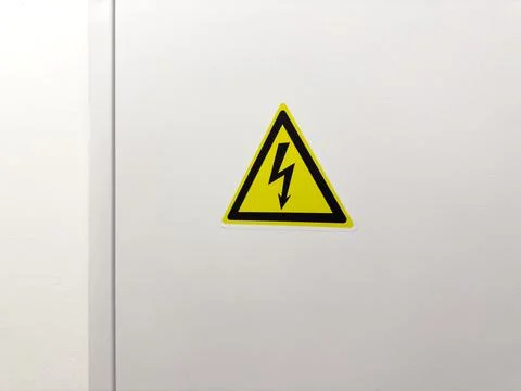 Yellow triangular high voltage sign with black lightning bolt on white electr Stock Photos