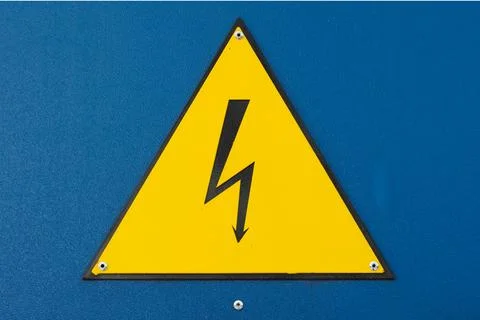 Yellow triangular high-voltage warning sign with a black lightning bolt Stock Photos