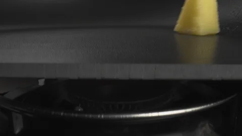 Yellow triangular piece of butter rolls over heated pan melt and become liquid Stock Footage 123573084