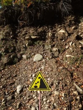 Yellow triangular warning sign stands on a hillside background Stock Photos