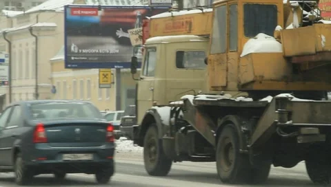 Yellow truck driving through downtown of city covered with white snow Stock Footage