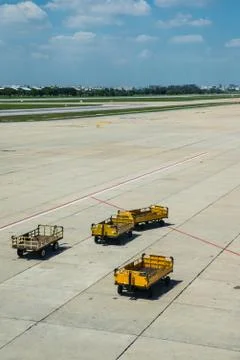 The yellow trucks wait for loading in the platform of airport Stock Photos