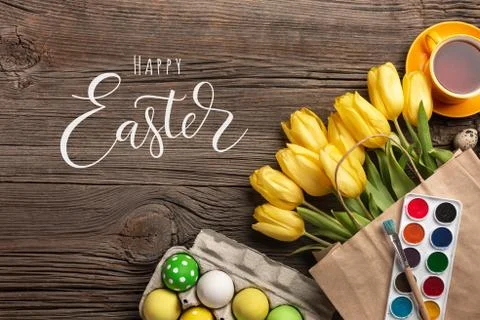 Yellow tulips, a nest with Easter eggs, bright colors and a palette on a wood Stock Photos