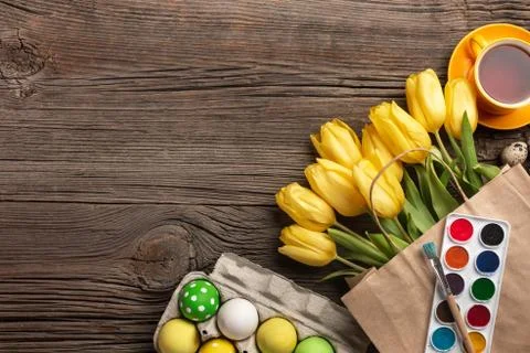 Yellow tulips, a nest with Easter eggs, bright colors and a palette on a wood Stock Photos