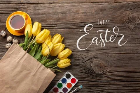 Yellow tulips, a nest with Easter eggs, bright colors and a palette on a wood Stock Photos