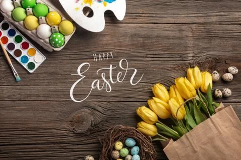 Yellow tulips, a nest with Easter eggs, bright colors and a palette on a wood Stock Photos