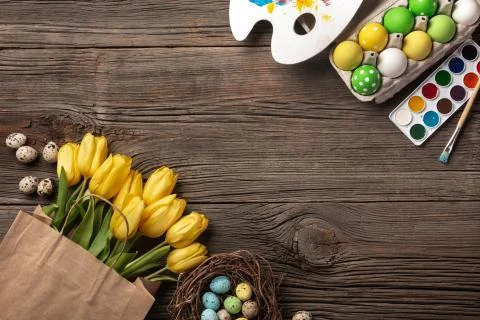 Yellow tulips, a nest with Easter eggs, bright colors and a palette on a wood Stock Photos