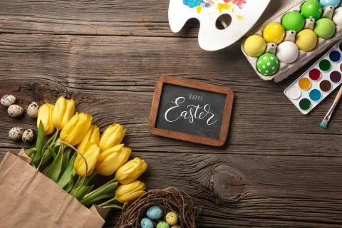 Yellow tulips, a nest with Easter eggs, bright colors and a palette on a wood Foto stock