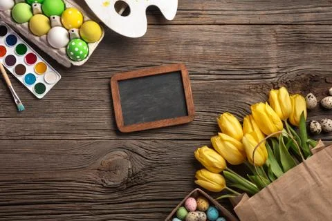 Yellow tulips, a nest with Easter eggs, bright colors and a palette on a wood Stock Photos