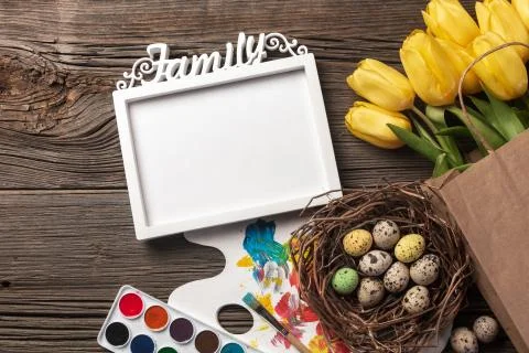 Yellow tulips, a nest with Easter eggs, bright colors and a palette on a wood Stock Photos