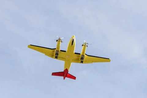 Yellow twin engine propeller plane flying in blue sky Stock Photos