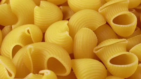 Yellow uncooked pipe rigate snail shape Italian pasta circle rotation Stock Footage 234780653