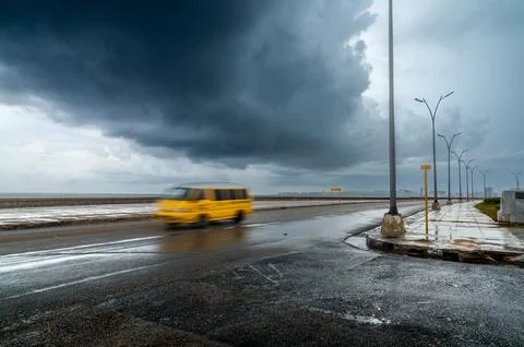 Yellow van driving on Malecon during stormy weather Photos