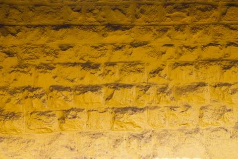 Yellow wall of large bricks with shadow. rough surface texture Foto stock