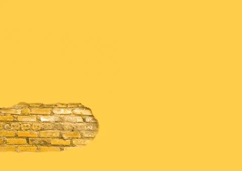 Yellow wall with a section of exposed brick Stock Photos