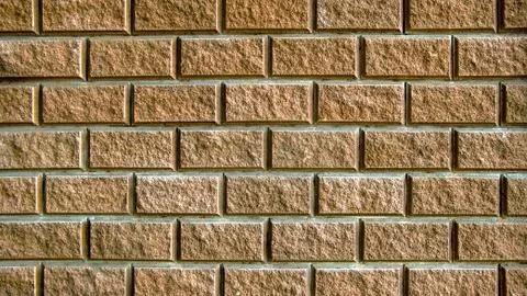 The yellow wall is tiled with torn bricks Foto stock