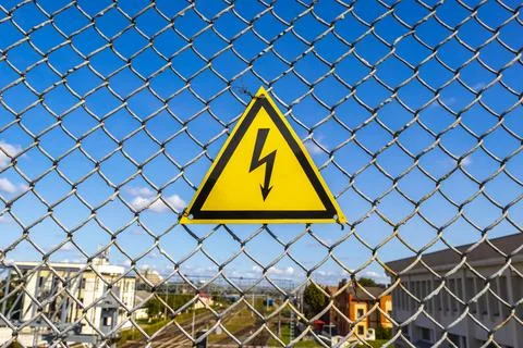 Yellow warning sign on the chain link fence in Belarus. Stock Photos