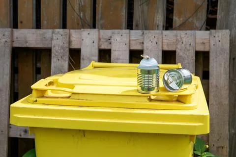 Yellow waste sorting container. Empty metal cans. Terms and duty Stock Photos