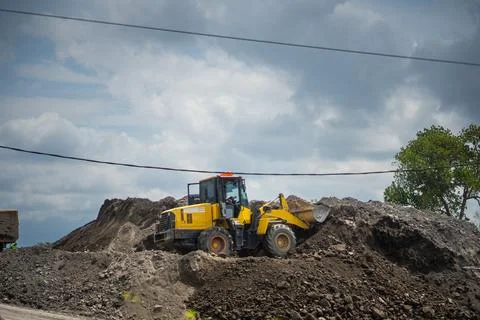 Yellow Wheel Loader Leveling Earth and Loading Soil Material into Tipper Tr.. Stock Photos