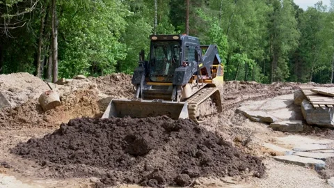 Yellow wheel loader parked on forest trail renovation site 스톡 동영상 311892829