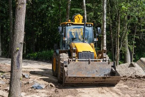Yellow wheel loader parked on forest trail renovation site Stock Photos