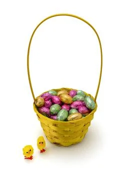 Yellow Wicker Easter Basket with Foil Wrapped Chocolate Eggs on White Stock Photos