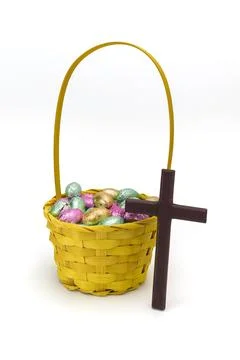 Yellow Wicker Easter Basket with Foil Wrapped Chocolate Eggs and Cross Stock Photos