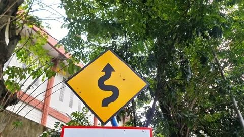 Yellow Winding Road Warning Traffic Sign with Green Tree Background Stock-Footage 332601501