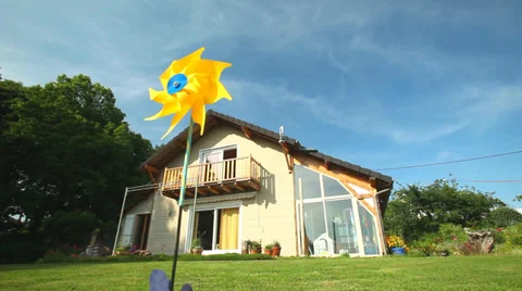 Yellow windmill spinning in wind in front of wooden house Stock Footage 35405956