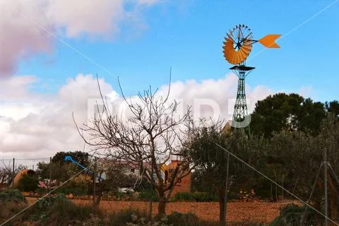 Yellow windmill with tale vane under cloudy and windy weather Stock Photos