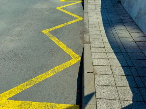 A yellow zigzag line marks the edge of the road next to a gray sidewalk. The  Stock Photos