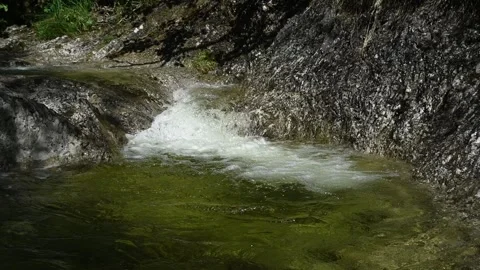 Yellowish water from a mountain stream flows into a pond (slow motion) Stock-Footage 260845083