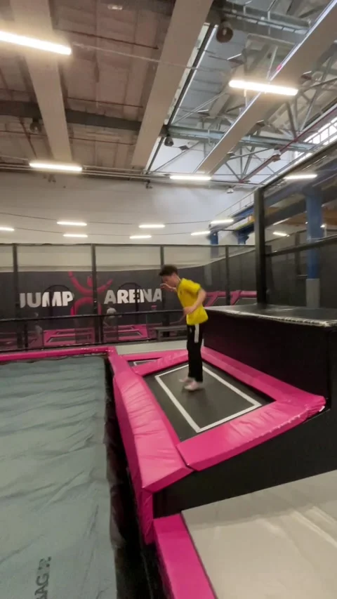 Yellowshirted instructor teaches proper technique for jumping safely into foam Stock Footage 335358614