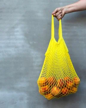Yelow mesh bag or string bag with ripe peaches in the women hand. Zero waste. Stock Photos