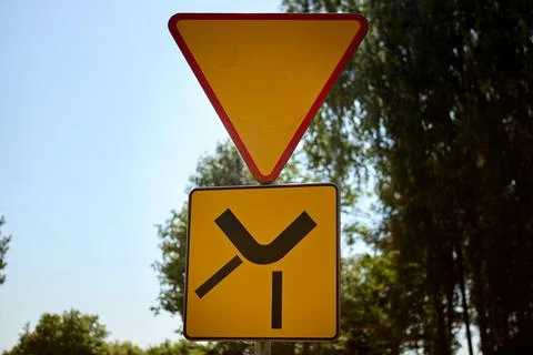 Yield sign with side road junction symbol on a sunny rural roadside Stock Photos