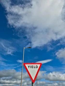 Yield traffic sign against dramatic blue sky clouds Stock Photos