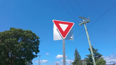 Yield traffic sign on metal post under clear blue sky Stock Footage 340155207