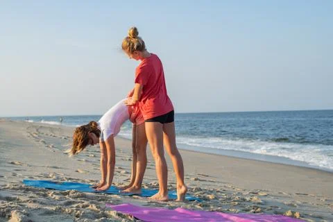 Yoga class instructor helps beginner to make asana exercises. Woman doing yog 写真素材