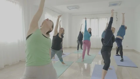 Yoga class made of middle aged women and a young man trying new poses and lis Stock Footage 87208662
