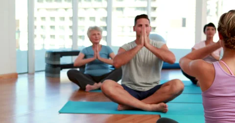 Yoga class sitting in lotus position together Stock Footage 34263564