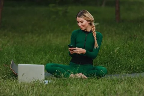 Yoga classes on the grass in the park using a mobile phone. Foto stock