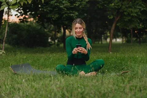 Yoga classes on the grass in the park using a mobile phone. Foto stock
