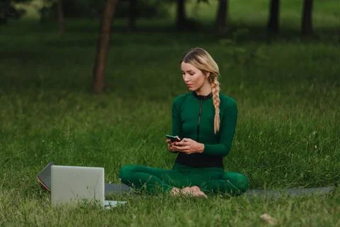 Yoga classes on the grass in the park using a mobile phone. Stock Photos
