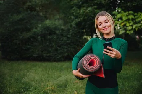 Yoga classes on the grass in the park using a mobile phone. Foto stock
