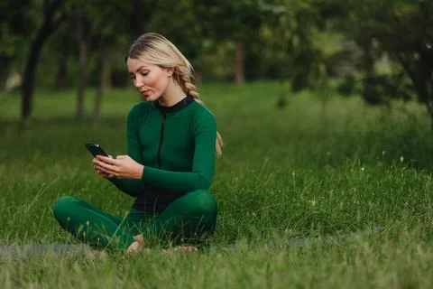 Yoga classes on the grass in the park using a mobile phone. Foto stock
