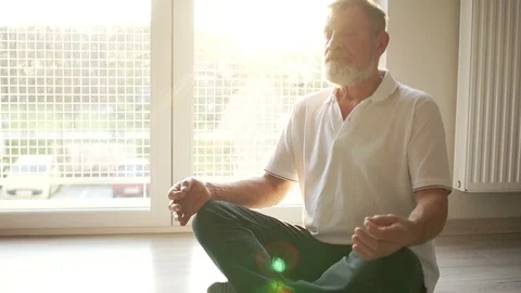 Yoga classes. Spiritual practice, an elderly yogi sits on the floor in a lotus Stock Footage 121452867